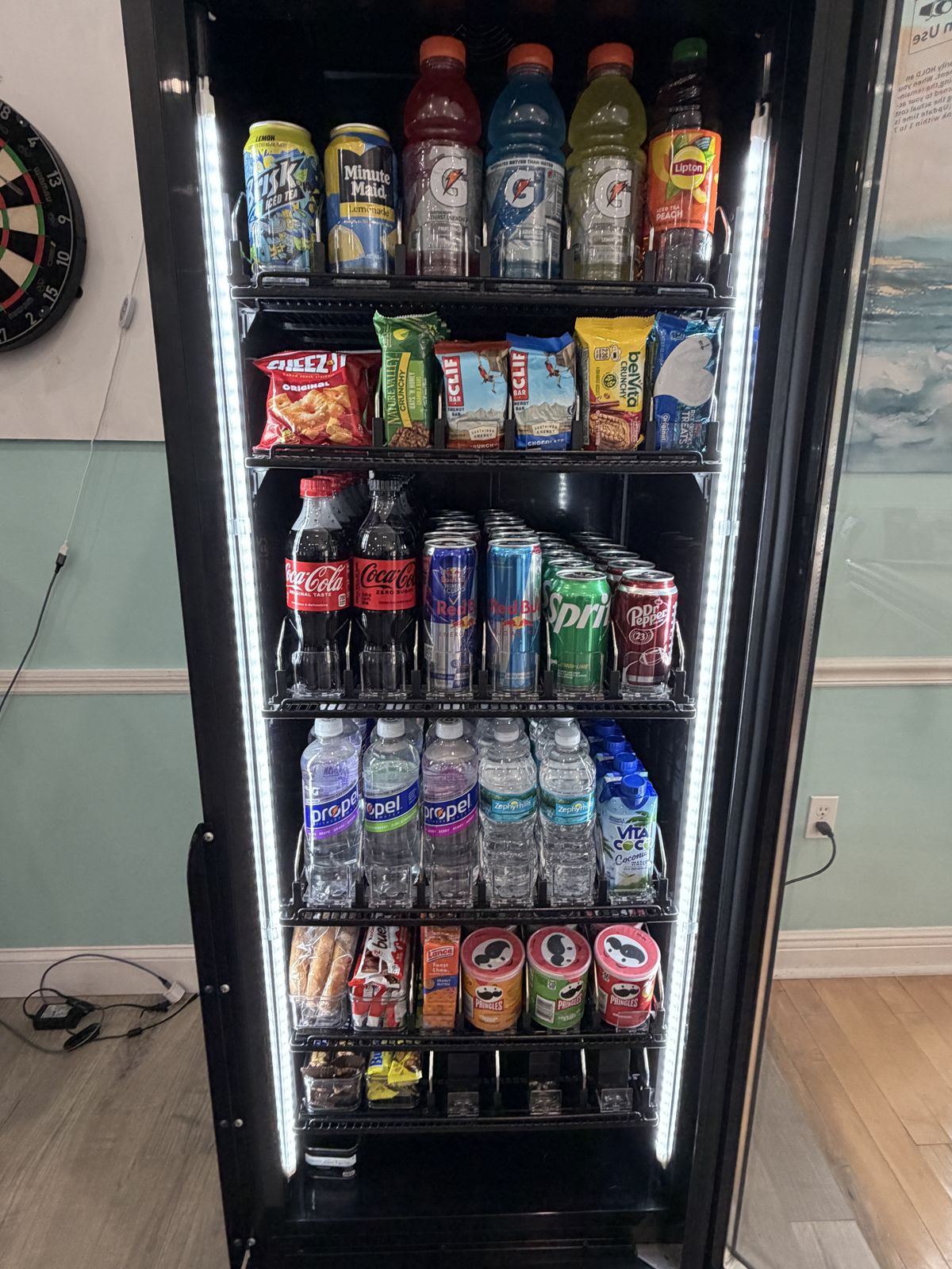 Smart fridge shelves stocked with Gatorade, Coca-Cola, Red Bull, Propel water, chips and snack bars.